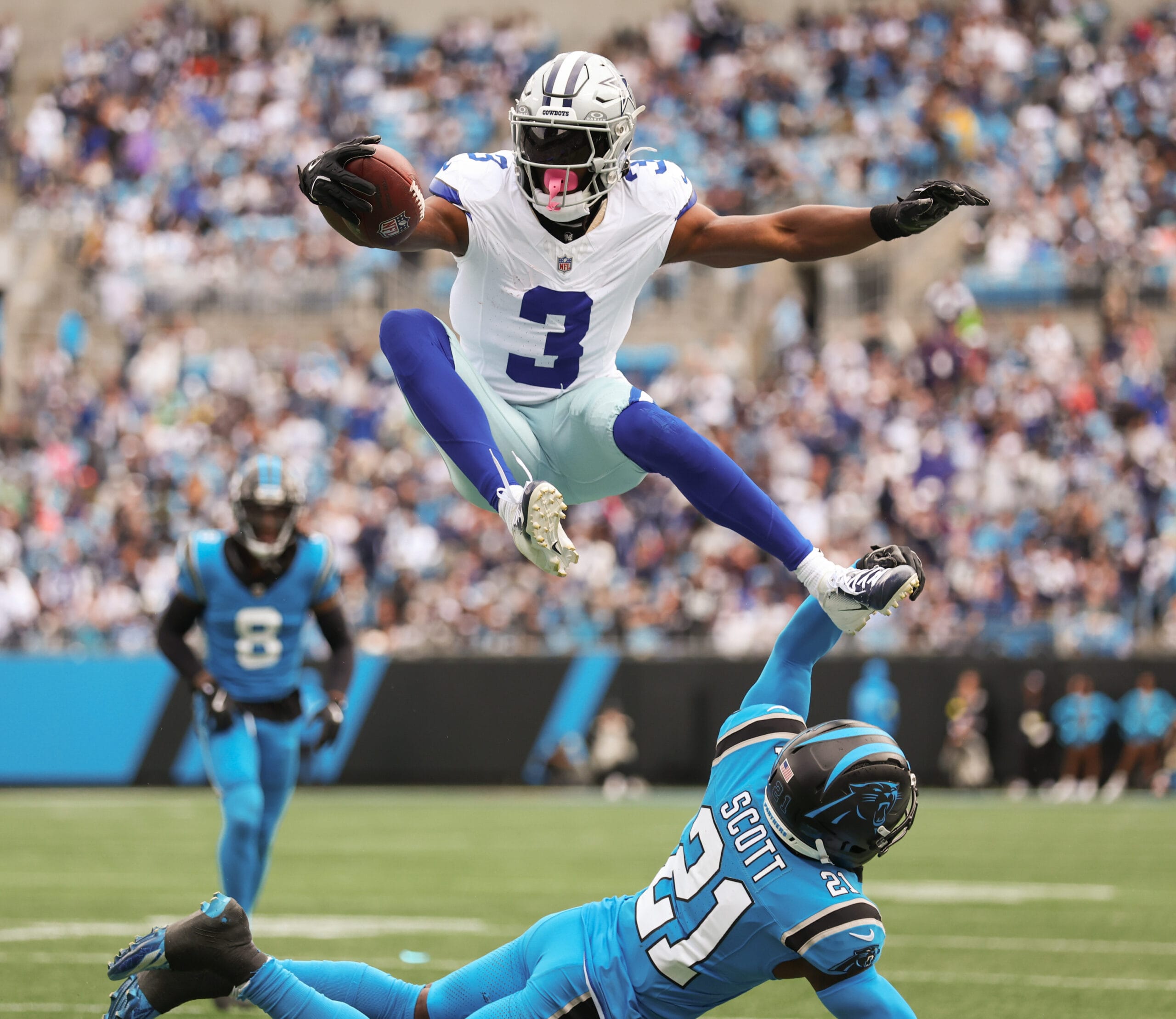 A Dallas Cowboys NFL football players leaps over a Carolina Panthers NFL football player. 